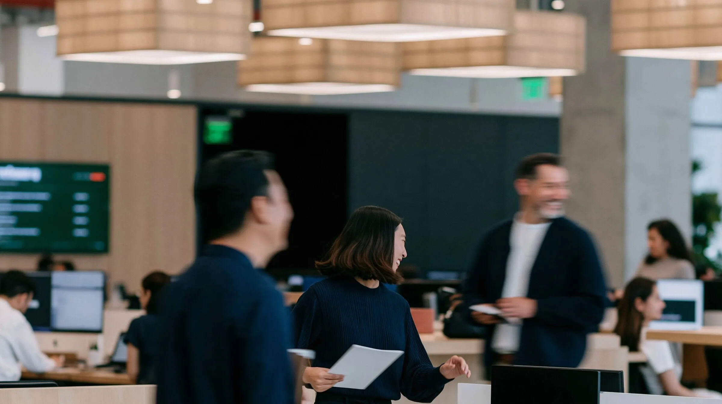 People talking and working in a bright open-plan office.